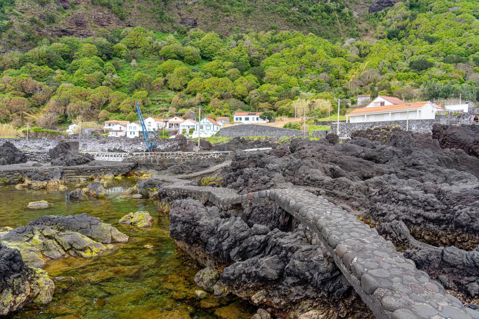 Volcanic rock formations on Terceira's coast forming natural sea pools — calm bathing spots carved by ancient lava flows meeting the Atlantic, Azores, Portugal